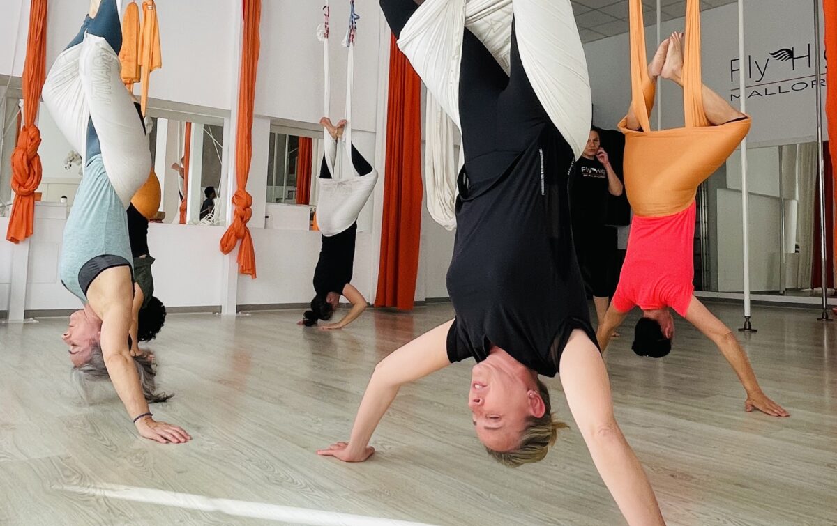 Persons doing antigravity fitnss Aerial yoga in a studio with Orange colorOrange silk