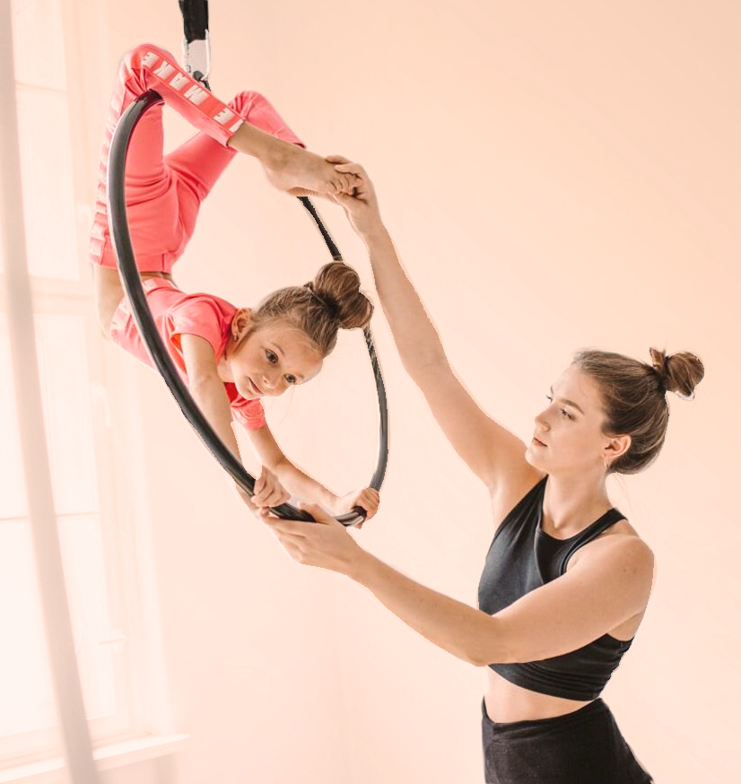 teacher help kids in aerial hoop class with beige background